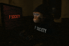 a monkey wearing a f society sweatshirt is typing on a keyboard