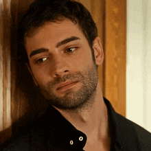 a man with a beard is leaning against a wall with his eyes closed