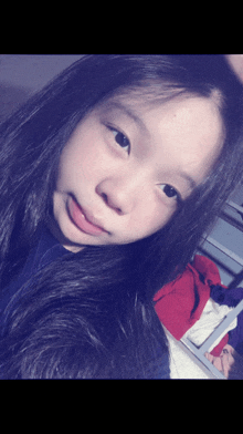 a girl with long black hair takes a selfie with her tongue out