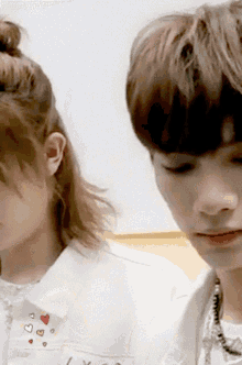 a boy and a girl are standing next to each other with hearts on their shirts