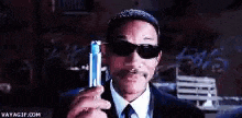 a man in a suit and tie is holding a blue lighter in his hand .