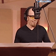a man wearing headphones and sunglasses stands in front of a microphone with a video bank logo on the bottom