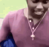 a man wearing a purple shirt and a necklace with a cross on it is smiling .