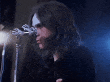 a close up of a person holding a microphone with a blue light behind them
