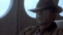 a man wearing a hat and sunglasses is sitting on a plane