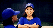 a woman wearing a blue hat that says sgmw is talking to another woman