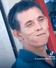 a man is making a funny face with his eyes closed while standing in front of a red ladder .