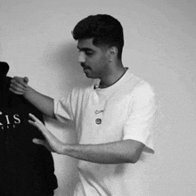 a man in a white t-shirt holds a black hoodie with the letter s on it