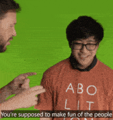 a man is pointing at another man who is wearing a shirt that says abo lit