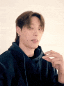 a close up of a person wearing a black hoodie and holding something in their hand .