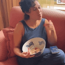 a woman sitting on a couch with a bowl of cereal
