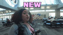 a woman stands in a room with the word new above her head