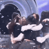 a group of young women are hugging each other on a stage .