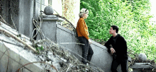a man and a woman are standing on a set of stairs and talking to each other .