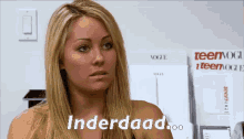 a woman with blonde hair says " underdaad " in front of a stack of teen vogue magazines