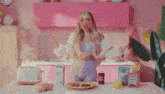 a woman is standing in a kitchen with her arms outstretched and a plate of food .