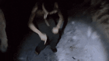 a man without a shirt is holding a knife in a dark room .