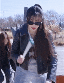 a woman wearing sunglasses and a leather jacket is holding a toothbrush in her hand .
