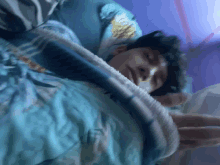 a man is sleeping in a bed with a blue comforter