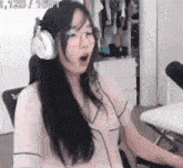 a woman wearing headphones and glasses is sitting in a chair in front of a microphone .