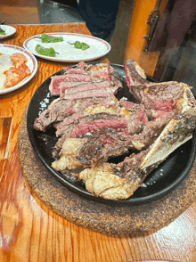 a large piece of meat is on a black plate on a table