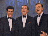 three men in tuxedos and bow ties sing together
