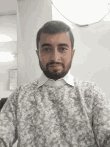 a man with a beard is wearing a sweater with a floral pattern