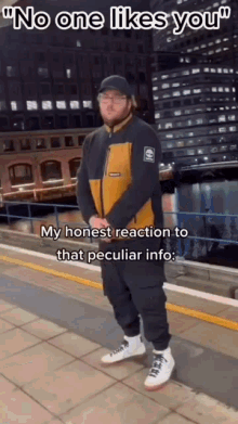 a man in a yellow and black jacket is standing on a sidewalk with a caption that says `` no one likes you '' .