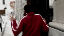 a man in a red jacket with white stripes runs down a street