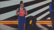 a woman in a blue dress is holding a pink piece of paper that says ' a ' on it