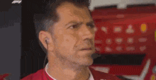 a man in a red jacket is wearing a headset and looking at the camera .