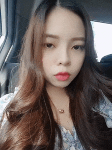 a woman with long hair is wearing a necklace with a ring on it