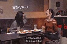 two women are sitting at a table with plates of food in a restaurant .