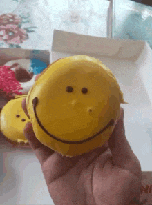 a person is holding a yellow smiley face donut