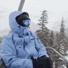 a person wearing a blue jacket and goggles is sitting in a ski lift