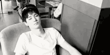 a black and white photo of a man sleeping on a couch .