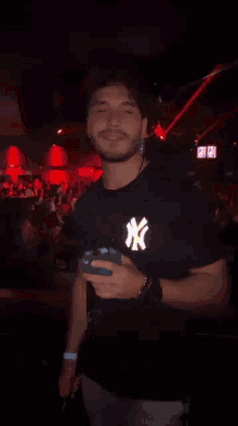a man wearing a black ny shirt is holding a blue bottle