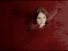 a woman in a red dress looks up at the camera