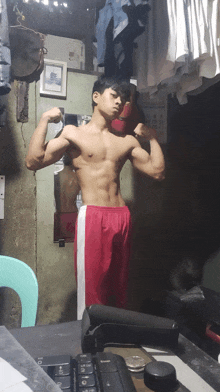 a shirtless man in red shorts flexes his muscles in front of a calendar that says july
