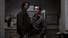 a man in a plaid shirt stands next to another man in a jacket