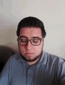 a man with glasses and a beard is sitting on a couch