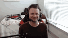 a man wearing headphones and a microphone is sitting in front of a microphone in a bedroom .