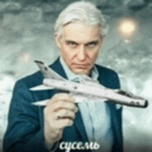 a man in a suit is holding a small model airplane .