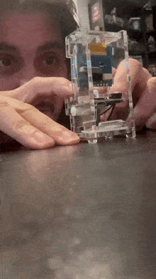 a man is holding a clear cube with a blue and white item inside of it