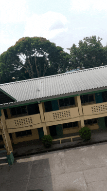 an aerial view of a building with a white roof and trees in the background
