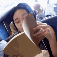 a woman is reading a book in a car