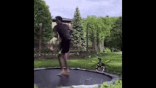 a man is jumping on a trampoline while a robot is flying in the background .