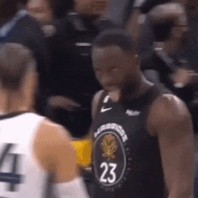 a basketball player in a black jersey with the number 23 on it is talking to another player .