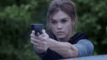 a woman is holding a gun in her hand and pointing it at someone .