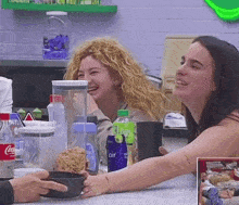 two women are sitting at a table with a coca cola bottle in front of them